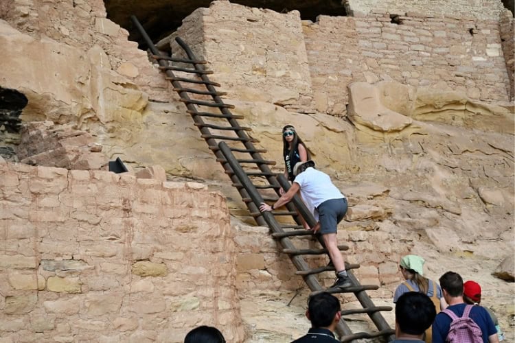 Climbing to the second level at a cliff dwelling with secure ladders. Photo by Tab Hauser
