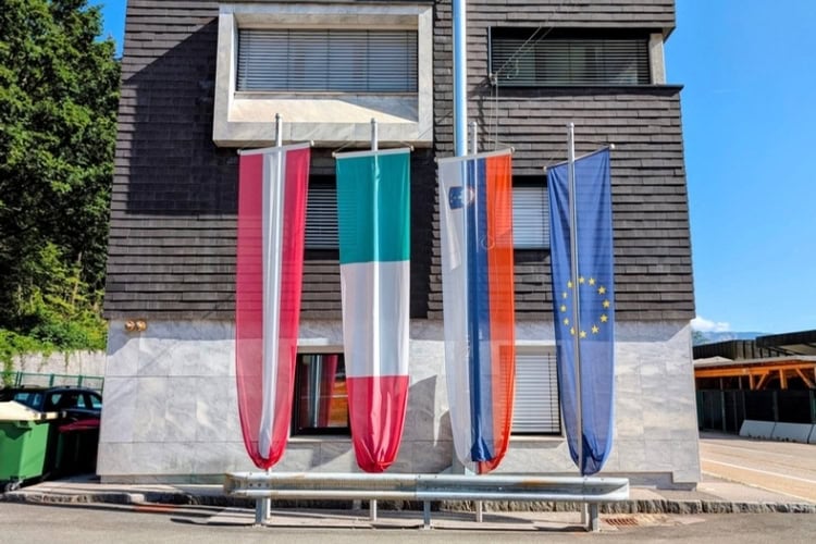 Banners representing the flags of Austria, Italy, Slovenia, and the European Union mark the border between Italy and Austria. Photo by Craig Stoltz