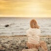 Woman sitting on the beach at sunset