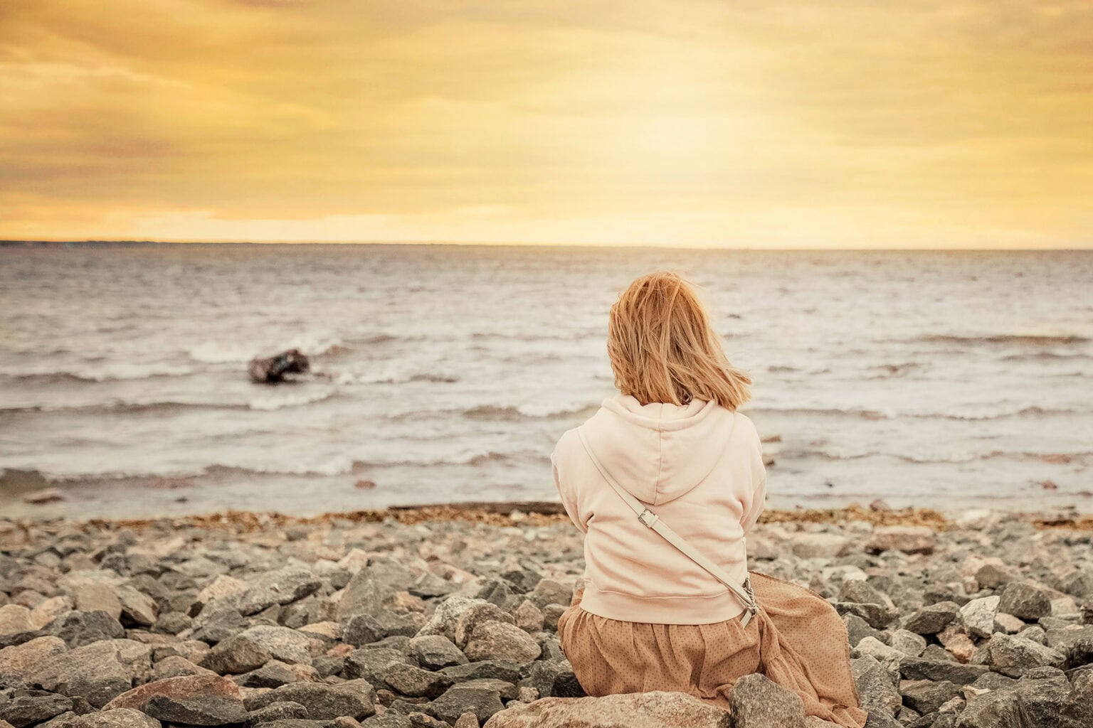 Woman sitting on the beach at sunset