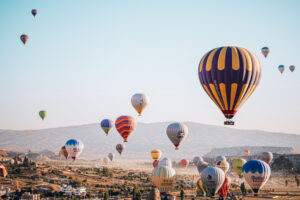 A scenic view of hot air balloons floating over Cappadocia at sunrise. Photo by Ibrahim Can Dayioglu, Pexels