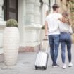 Couple with suitcase walking along city street. Photo by Andrea Piacquadio, Pexels