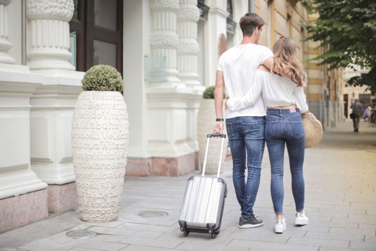 Couple with suitcase walking along city street. Photo by Andrea Piacquadio, Pexels