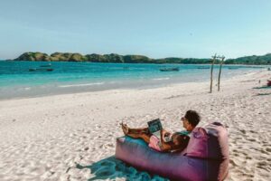 Man sitting on a bean bag on the beach. Photo by Johnny Africa, Unsplash