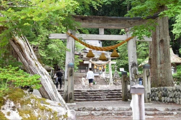 Visitors enter the sacred grounds of Shirakawa Hachiman Shrine, framed by a traditional torii gate. Photo by Masayoshi Sakamoto